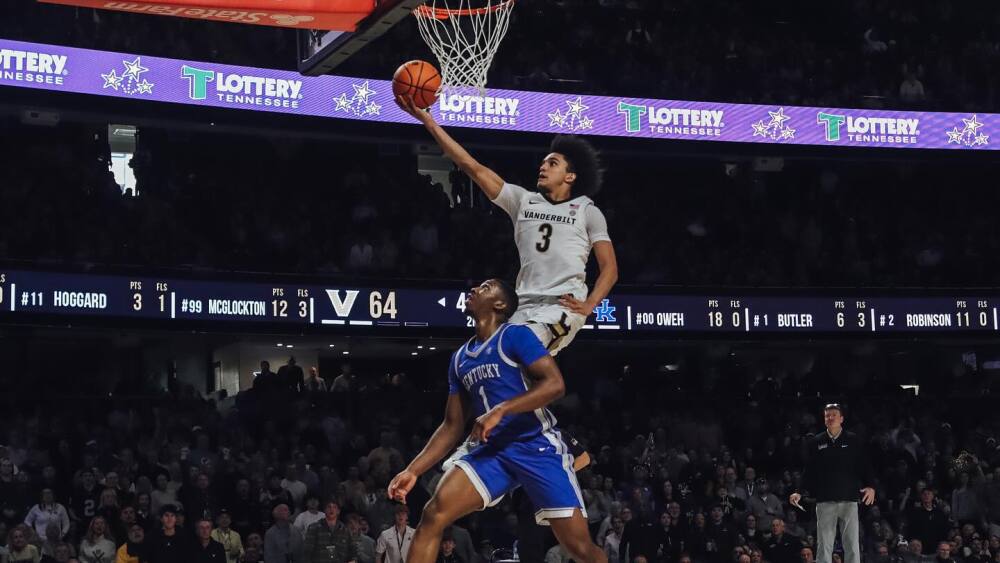 Vanderbilt's Tyler Tanner goes in for an underhand dunk or layup as Kentucky's Lamont Butler stands in front of him beneath the basket looking up at the net.