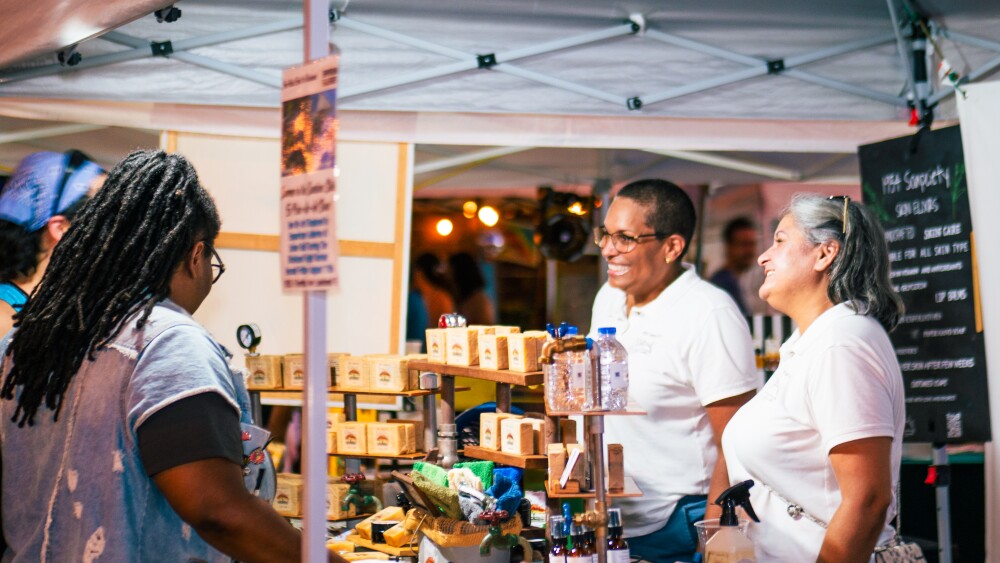 Two smiling vendors talk with customers at the Dixieland Night Market.