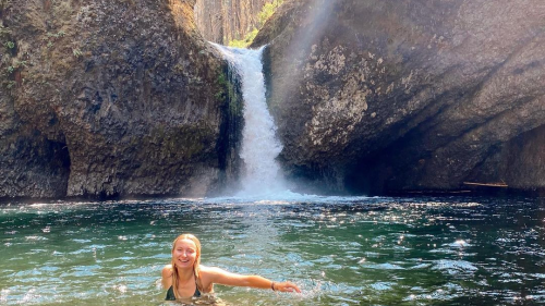 A woman swims in the swimming hole beneath Punchbowl Falls.