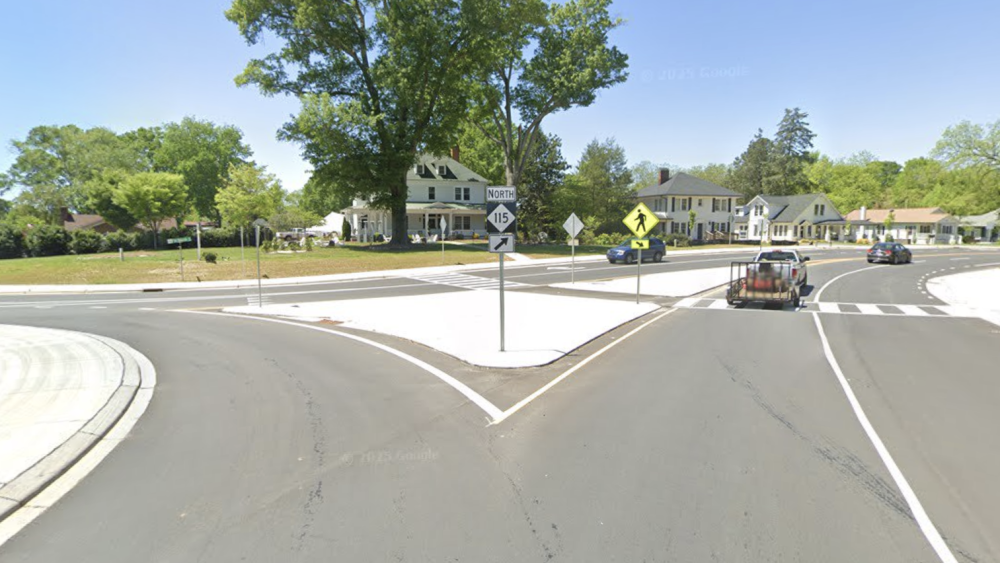 An empty road leading to a roundabout on the left and a street on the right.