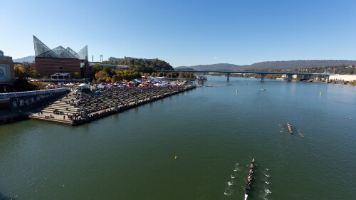 NOOGAtoday | rowers paddling across Tennessee River with crowd on the shore.