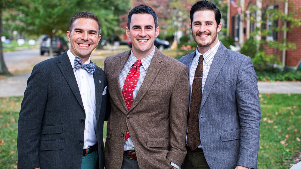 Three men and two women standing together smiling.