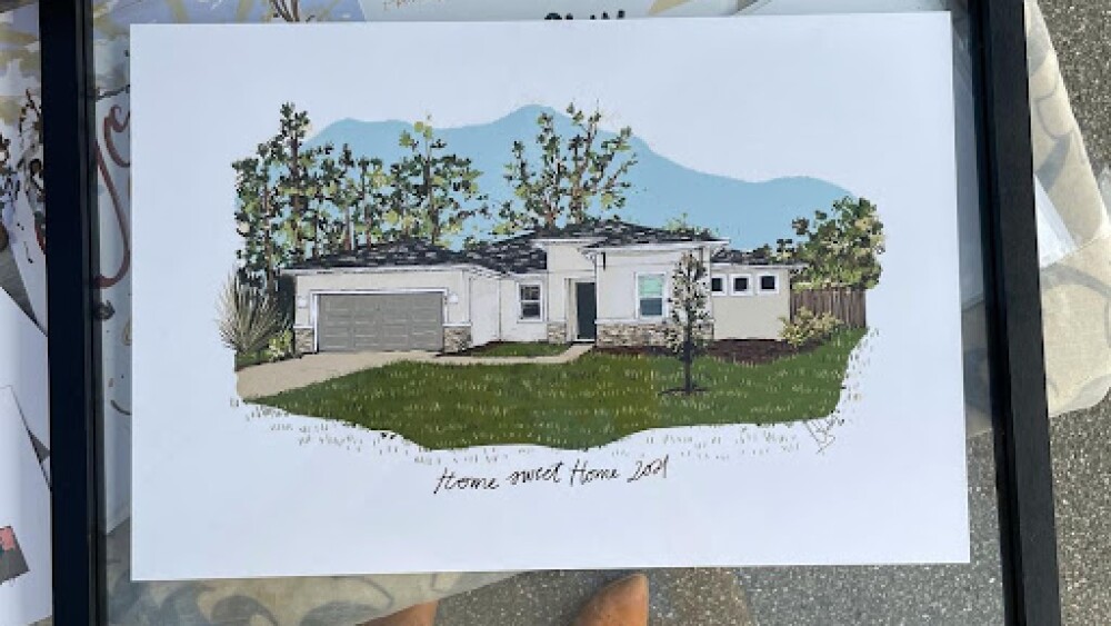 A framed color painting of a ranch style home surrounded by trees and a lawn.