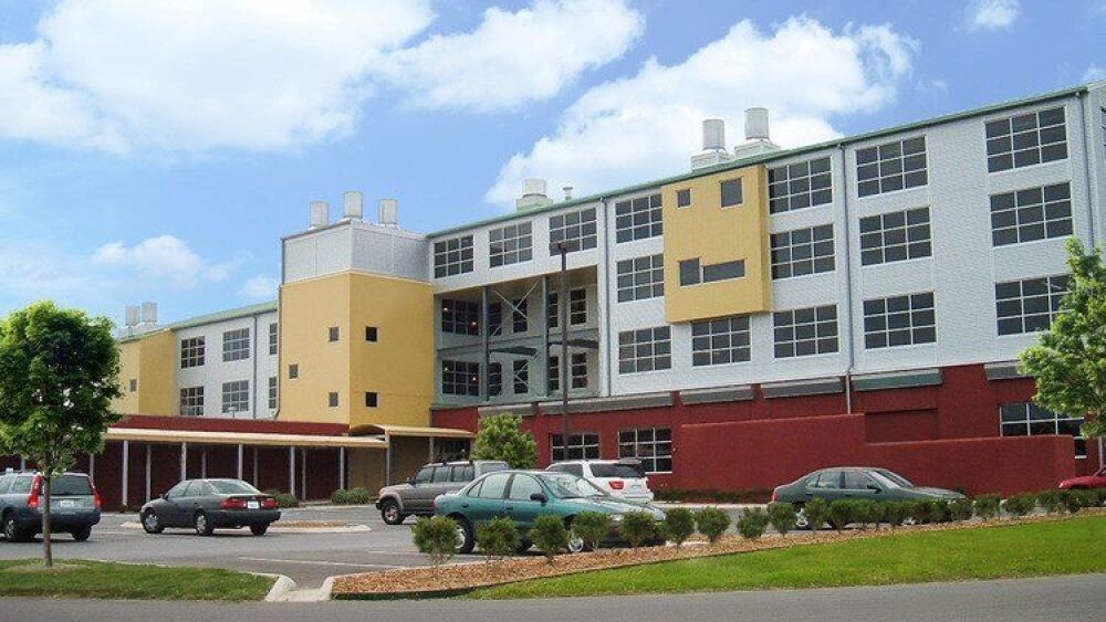 A large yellow and grey building with cars in front.
