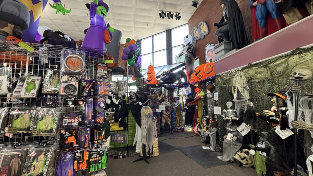 Aisles of costumes lining a walkway with Halloween decorations.
