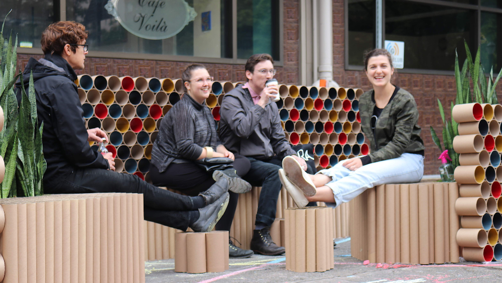 People sit in a pop-up park made of painted cardboard tubes.