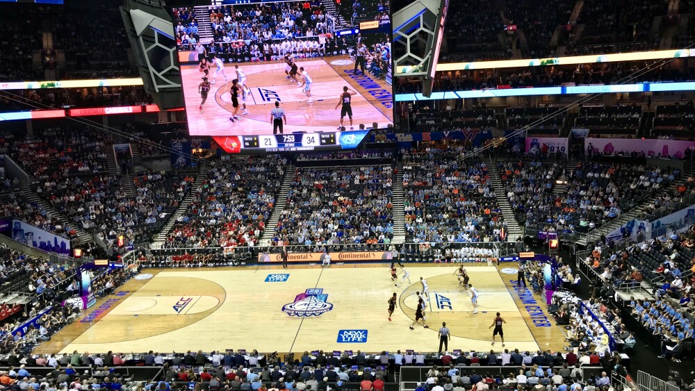 A crowd is gathered in Spectrum Center watching college basketball athletes compete on the court.