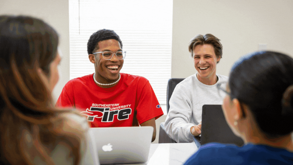 Photo 1: 4 college students sit at a table with laptops, two with their back to the camera and two facing the camera, one in a red tshirt that say "Southeastern University Fire" and one in a grey sweater. Photo 2: Two students walk down the sidewalk of a college campus in Florida, surrounded by palm trees and greenery. Both carry bags. Photo 3: A college student sits at a table looking at an open laptop, with books beside her on the table.