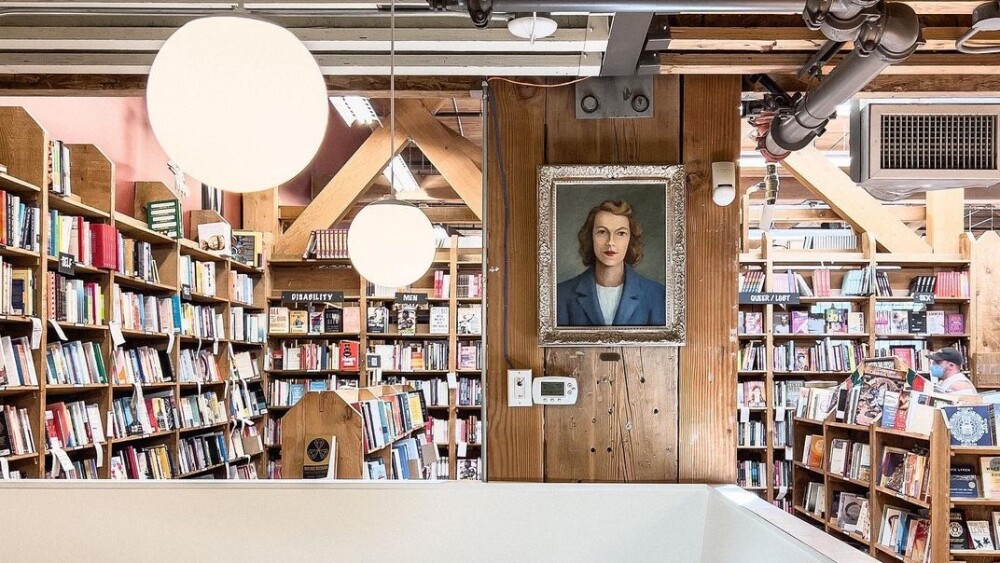 Shelves of books and a painting in the background; a white cafe booth in the foreground