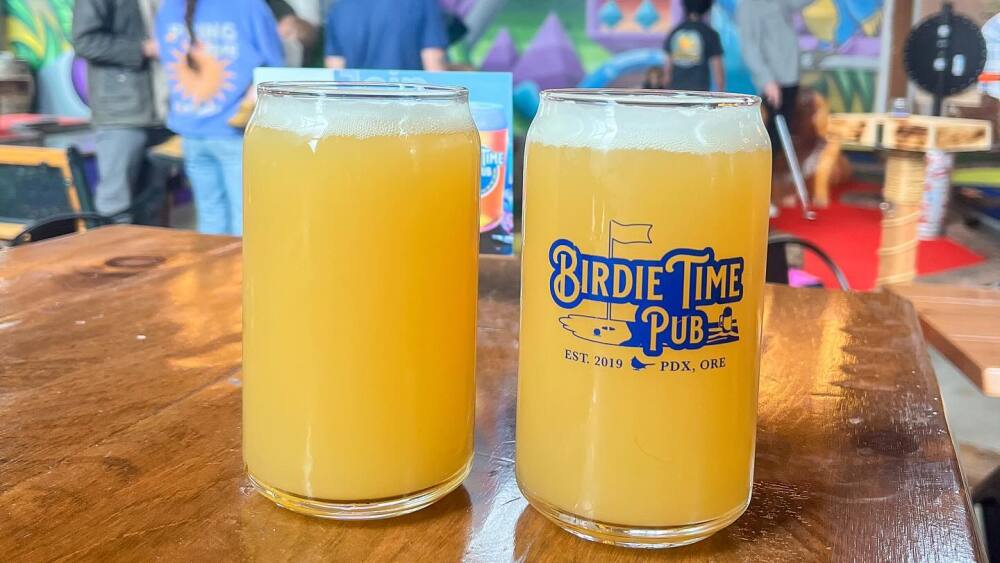 Two beers in glasses on a table with rhe "Birdie Time Pub" golf logo.