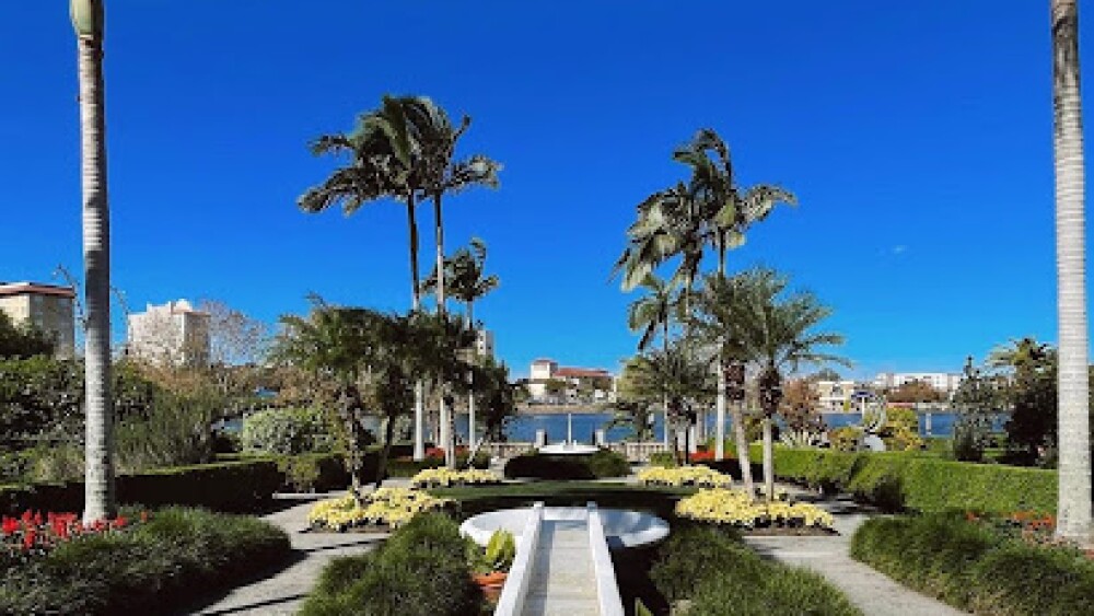 A white fountain moves water from pool to pool, framed by palm trees.