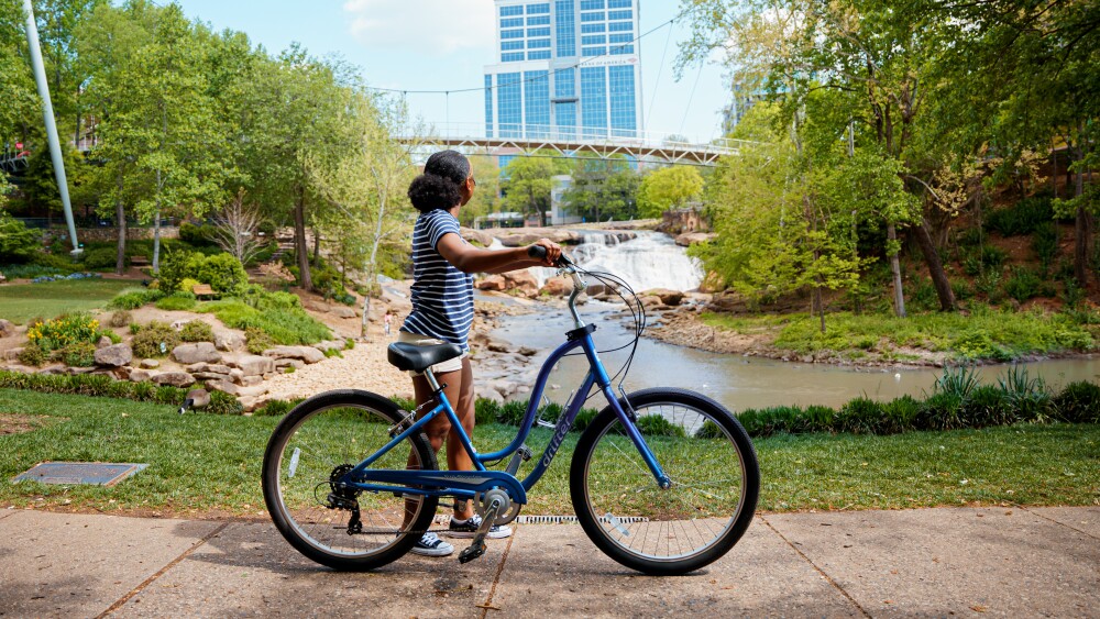 A woman standing by her bike at Falls Park in Greenville, SC.
