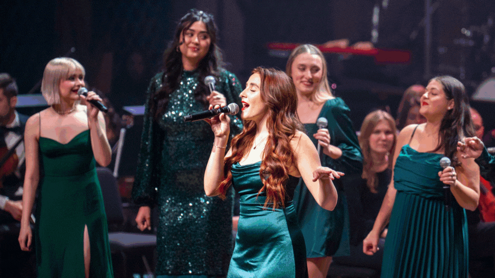 A gif of images showing Belmont University students singing in red and green dresses and costumes.