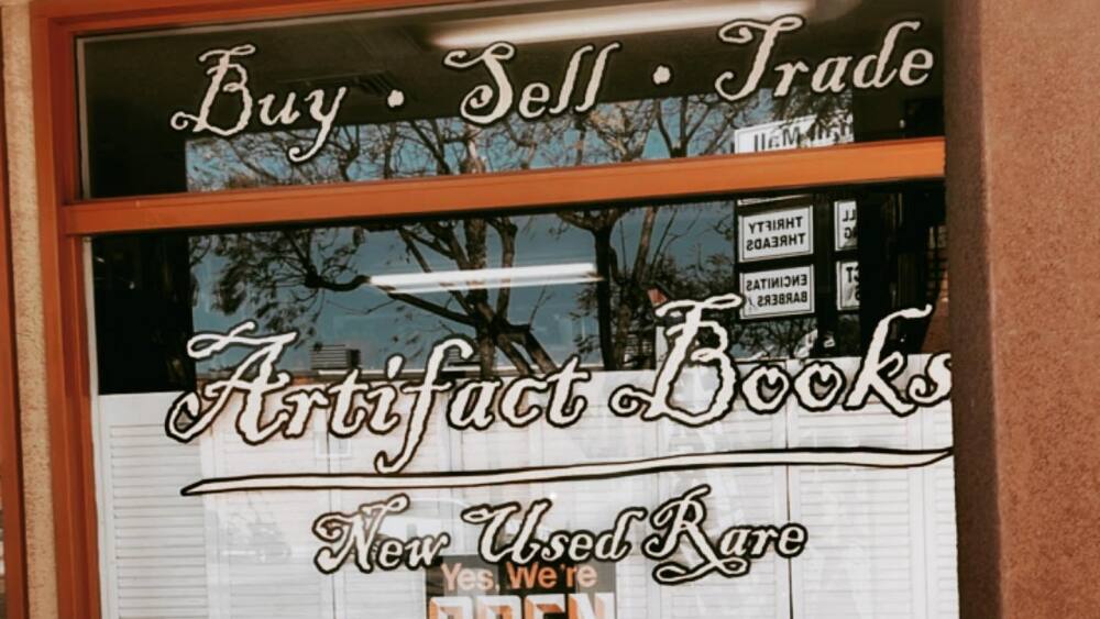 Artifacts books storefront with sign saying it buys and sells books.