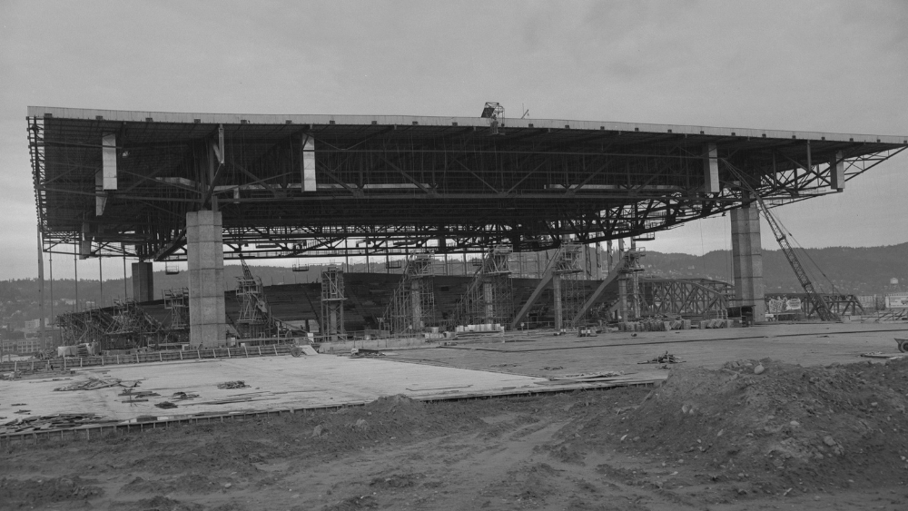 A historic photo shows Portland's Memorial Coliseum during construction. The structure's roof sits atop four massive pillars.