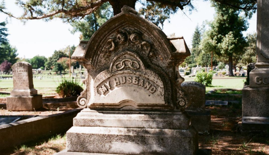 A gravestone reads "MY HUSBAND"