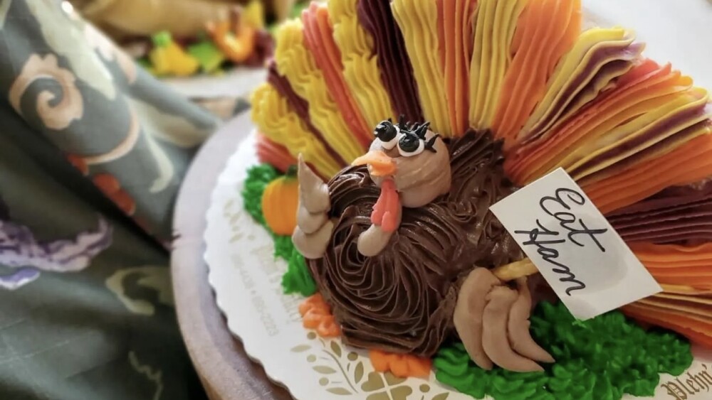 Turkey-shaped cake with a turkey holding a sign that reads "eat ham"