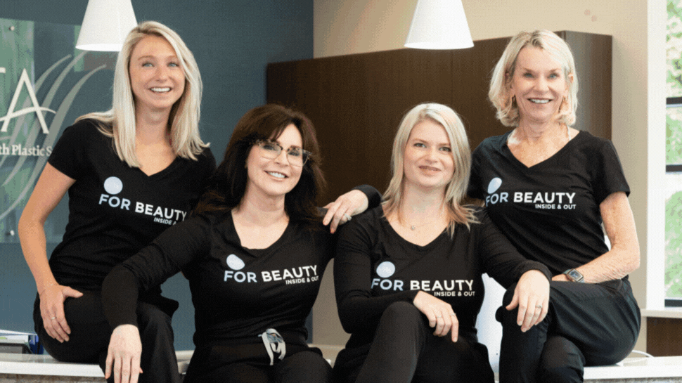 Four people smile at the camera. Four doctors smile at the camera in an operating room.