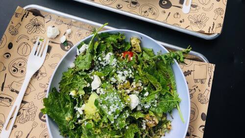 Two salads from Homegrown Seattle sit on a black table
