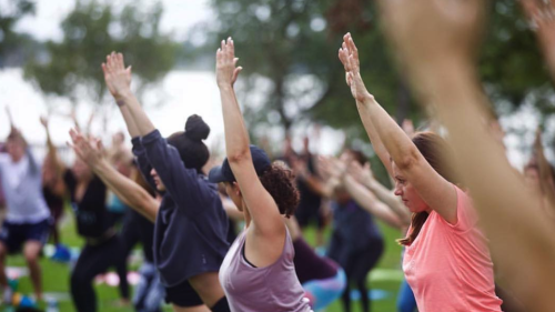 Women work out in an outdoors yoga class.