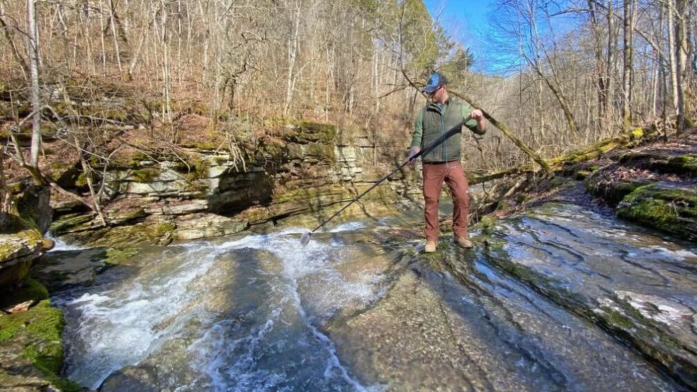 A person holding a microphone to a stream.