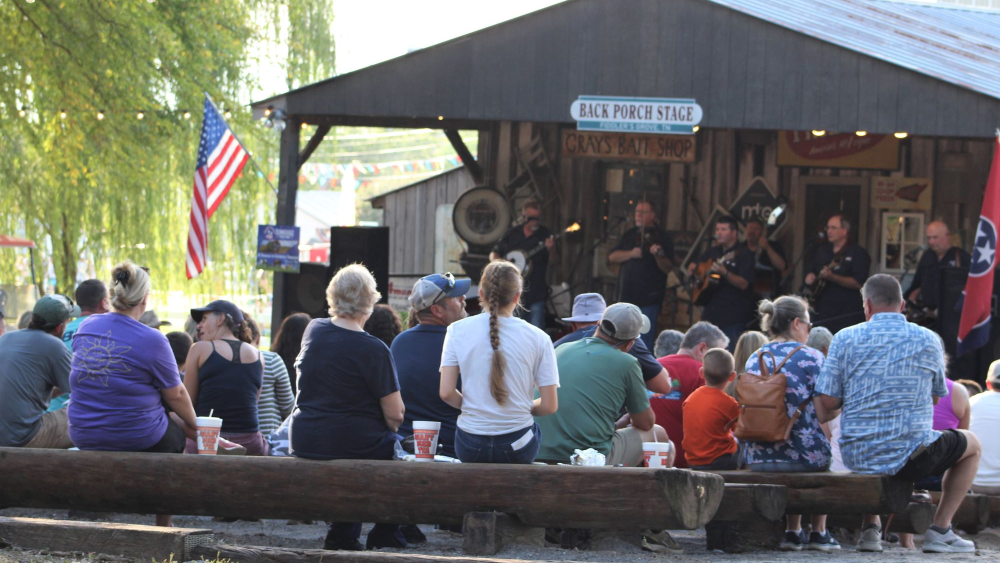 the backs of people watching a band perform on a covered stage.