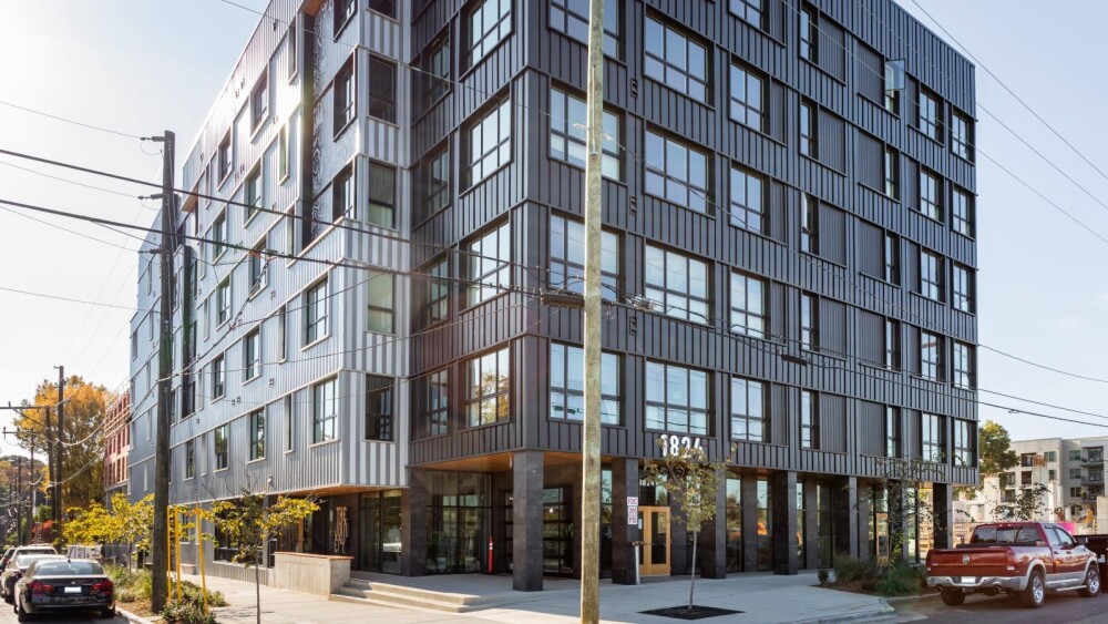 An exterior photo of an apartment complex with black and gray siding.
