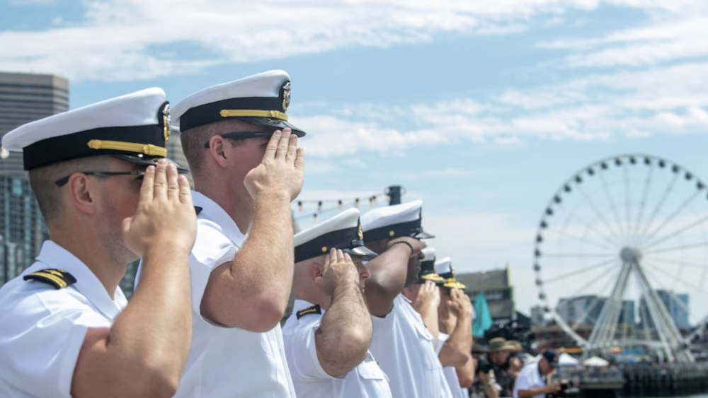 US Navy sailors give a salute with the Seattle Great Wheel in the background
