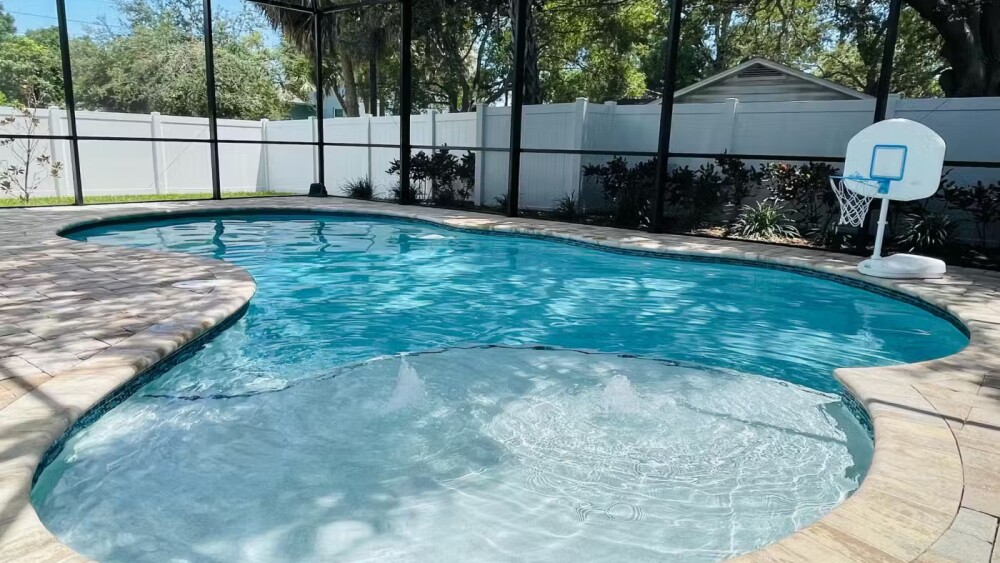 A large South Tampa pool is screened in and a little basketball hoop sits beside it.