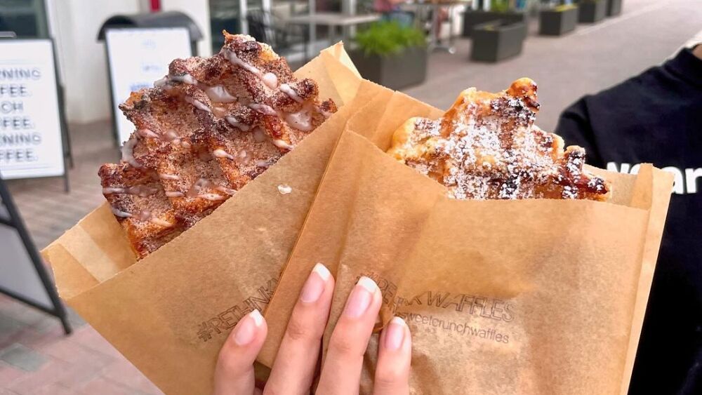 A person holding two waffles from a bakery in Charlotte, NC.