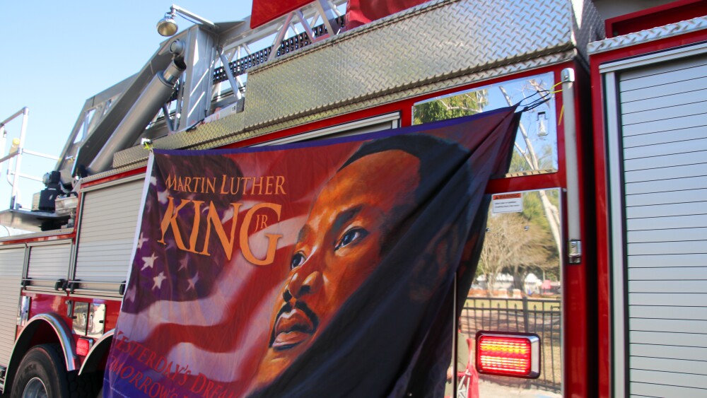 A sign featuring Martin Luther King Jr. hangs on a fire truck during a parade