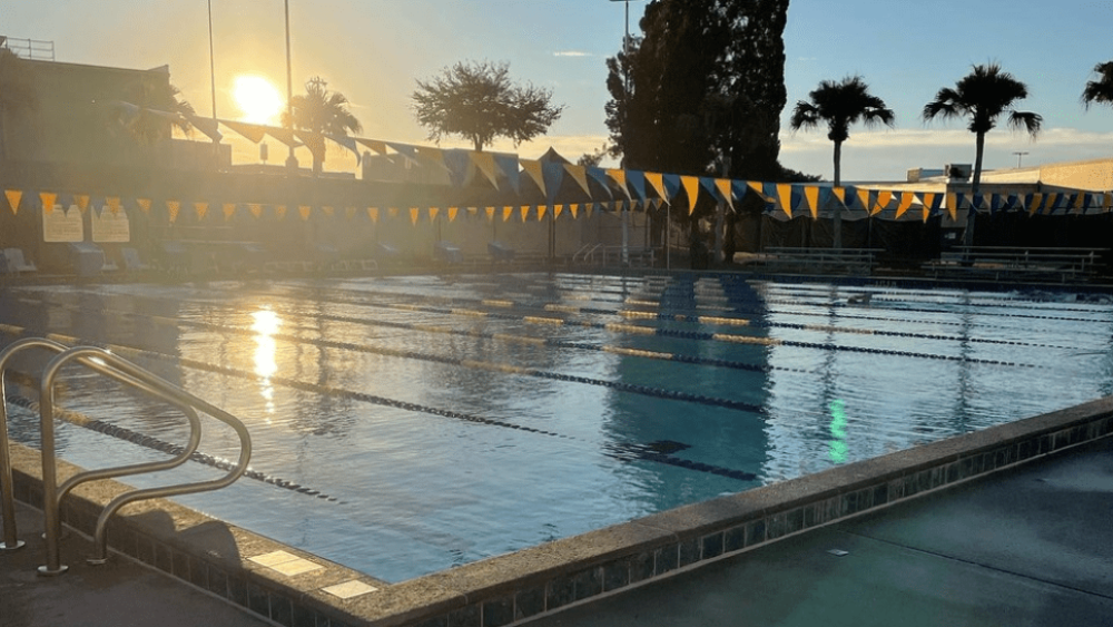 Sunrise over palm trees and swimming lanes lined with blue and yellow pennant flags Gandy Pool in Lakeland, FL