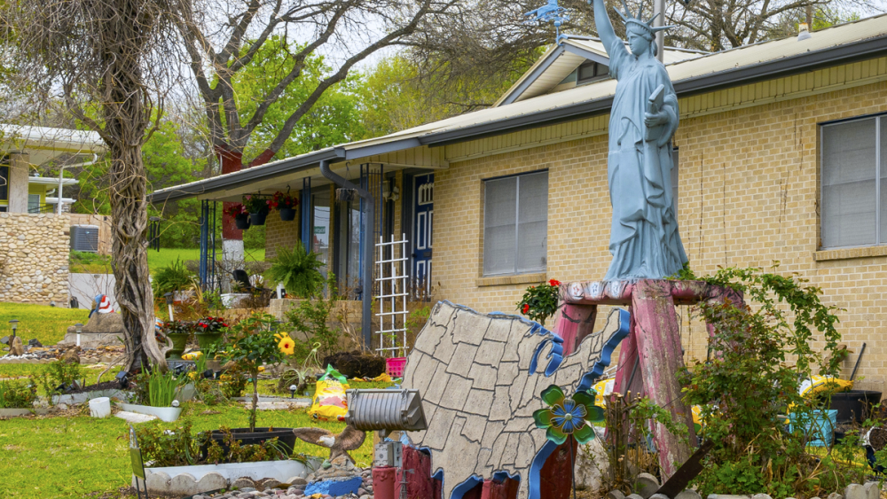 The Poole house, which features America-centered decor outside, including a small statue of liberty and stone map of the US, in a lush garden.