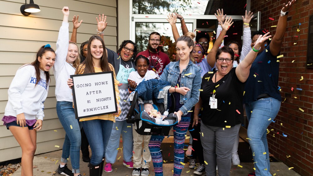 a group of people cheer around a mom holding a baby