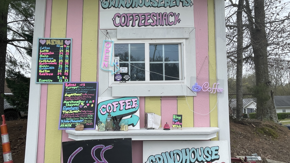 Pink and white striped shack with menu and signs.