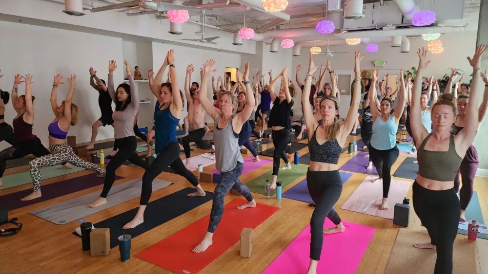 A group of students strike a pose on brightly colored mats during a yoga class.