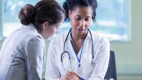 A woman sitting and talking with her doctor.