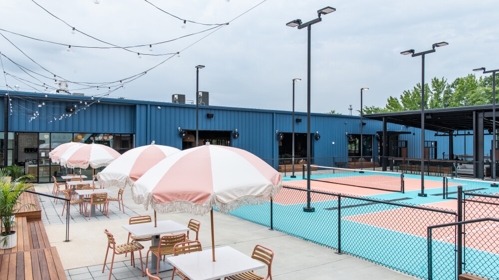 Two outdoor pickleball courts with umbrella tables.