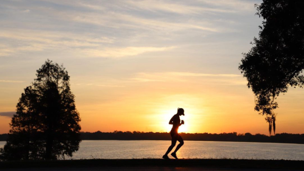 A silhouetted runner on Lake Hollingsworth at sunset