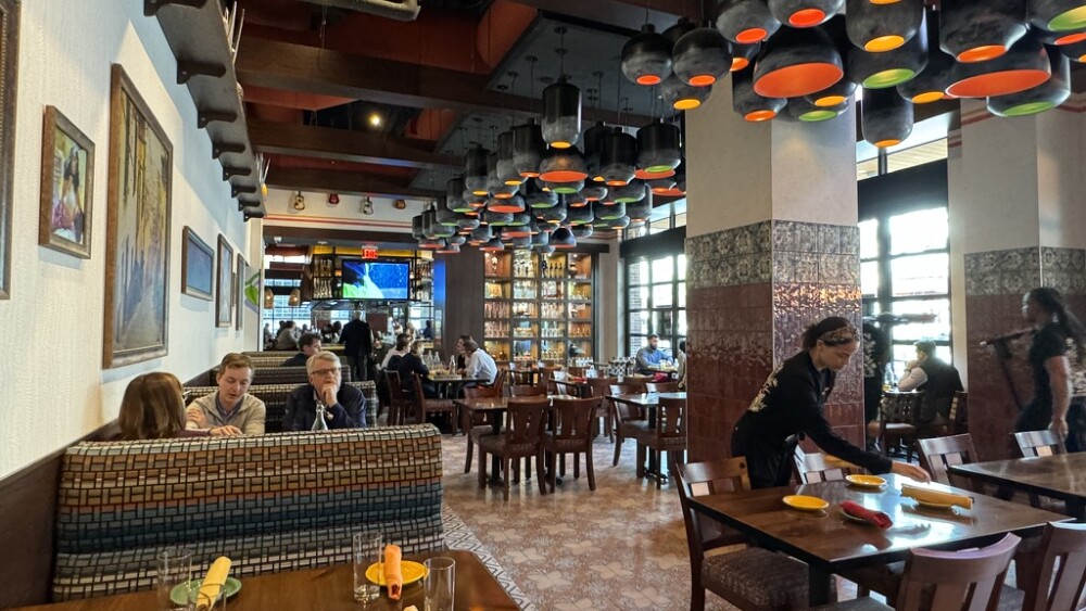 An interior shot of a restaurant with people sitting in booths and staff cleaning tables.