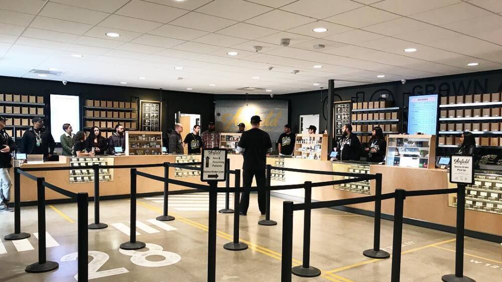 The inside of Airfield Dispensary showing several budtender counters and line stanchions.