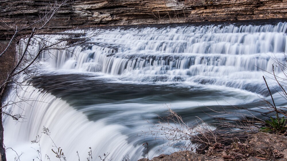 The very top of Burgess Falls with water running down the layered rock to a plateau before cascading down into another section of the waterfall.
