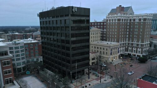 Aerial shot of current city hall building (tall, multi-story, black mid-century building)