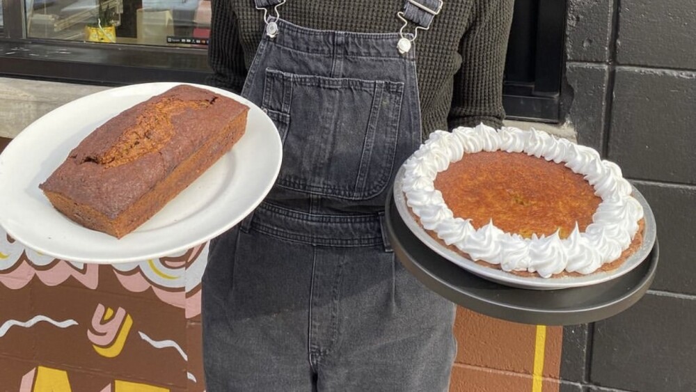 Woman holding a pumpkin loaf on a white plate and a pie with whipped cream in the other