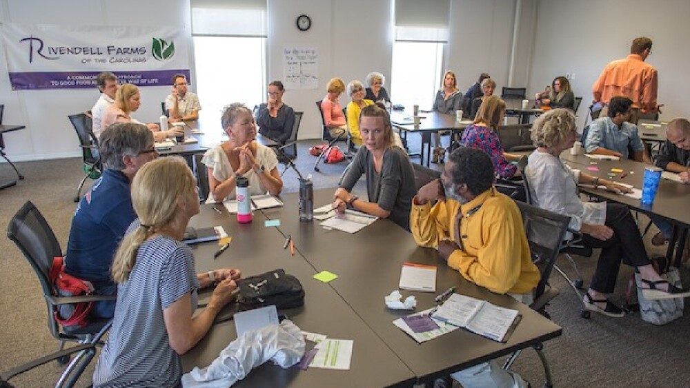 Groups of people gather around tables in a large room.