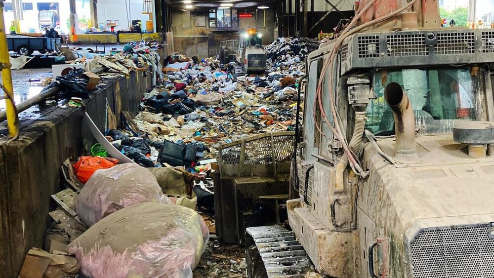 Heavy machinery pushes a pile of plastic materials at a material recovery facility.