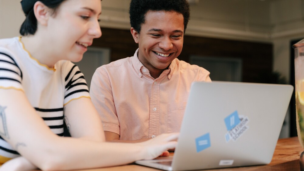 two students look at a laptop