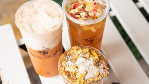 Three coffee drinks sitting on top of a white picnic table.