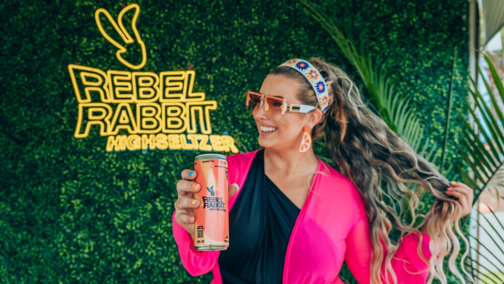 a woman holding a can of rebel rabbit 