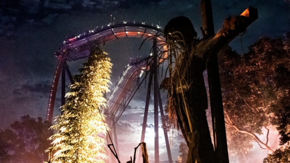 Scarecrow on a crucifix in front of a rollercoaster at Busch Gardens at night in 2022